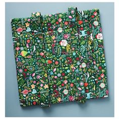 three green napkins with christmas designs on them sitting next to each other in front of a blue background