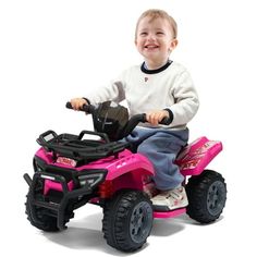 a young boy riding on the back of a pink toy atv