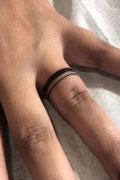 a person's hand with a black band on their left wrist and a ring on the middle finger