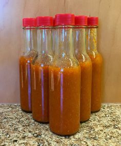 four jars filled with sauce sitting on top of a counter