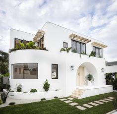 a white house with plants on the roof and stairs leading up to the front door