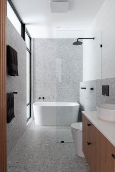 a bathroom with a white bath tub sitting next to a toilet and sink under a window