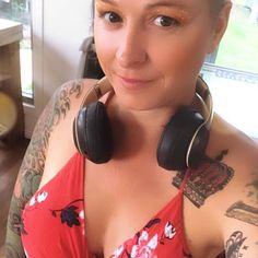 a woman with tattoos and headphones on her neck posing for a photo in front of a window