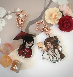 two pin badges sitting on top of a table next to a rose and other items