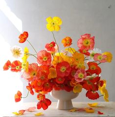 a white vase filled with lots of colorful flowers