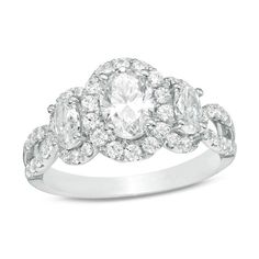 a white gold ring with three oval cut diamonds on the band and an oval shaped center stone