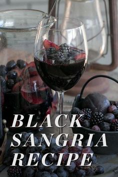 there is a glass of black sangria next to some berries