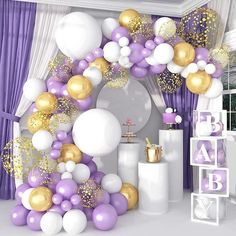 a baby shower is decorated with purple and gold balloons, streamers, and confetti