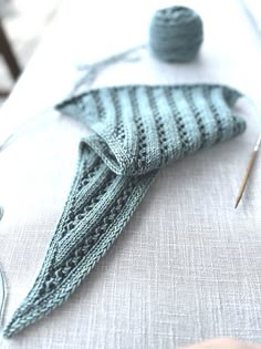 a knitted sock sitting on top of a table next to knitting needles and yarn