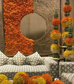 an arrangement of orange and white flowers on display in front of a large round mirror