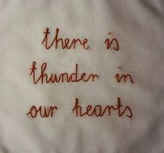 there is no thunder in our hearts embroidered on a white piece of cloth with red thread