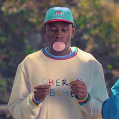 a man wearing a white shirt with the word cherry bomb on it and chewing a pink bubble