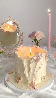 a white cake sitting on top of a table covered in frosting and flowers next to a mirror