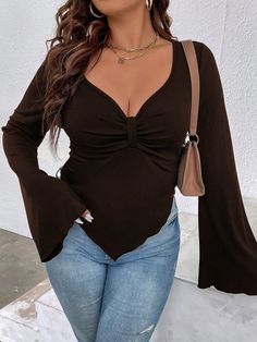 a woman in jeans and a brown top posing for the camera with her hands on her hips