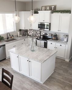 a kitchen with white cabinets and marble counter tops