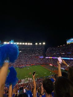 fans at a football game are holding up their cell phones