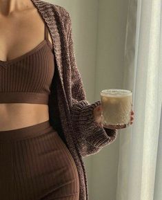 a woman holding a drink in her right hand and looking at the camera with no bra