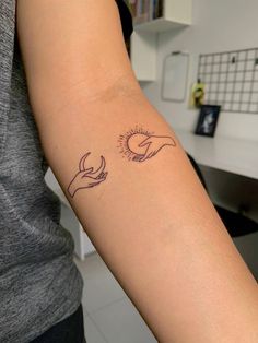 a woman's arm with two hands holding the sun and moon tattoo on it