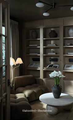 a living room filled with lots of furniture and bookshelves next to a window