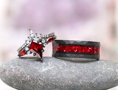 two red and white rings sitting on top of a rock next to each other,