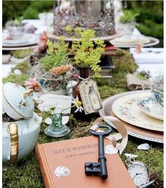 an open book sitting on top of a lush green field next to a bunch of flowers