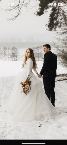 a bride and groom holding hands in the snow