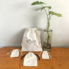 a vase with a plant in it next to two drawstring bags on a table