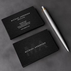 two business cards and a pen on a table