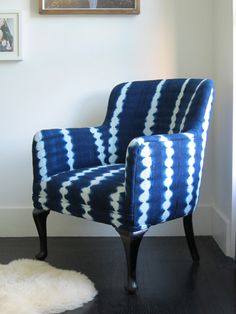 a blue and white chair sitting on top of a hard wood floor next to a painting