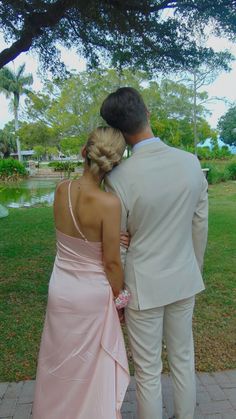 a man and woman in formal wear standing next to each other on a brick walkway