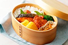 a bento box filled with rice, meat and vegetables on top of a blue napkin