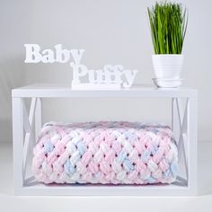 a crocheted blanket sitting on top of a table next to a potted plant