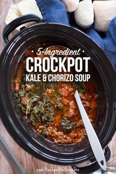 a crock pot filled with kale and chorizzo soup on top of a wooden table