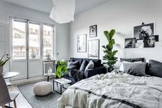 a bed room with a neatly made bed next to a couch and a table in front of a window