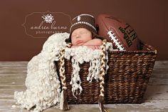 a newborn baby is sleeping in a basket with footballs