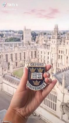 a person holding up a small badge in front of a cityscape with the words oxford on it