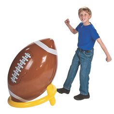 a young boy standing next to an inflatable football