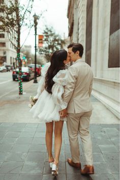 a bride and groom kissing on the street