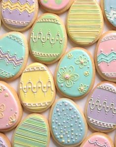 decorated cookies with pastel colors and designs are displayed on a white tablecloth in this close up photo