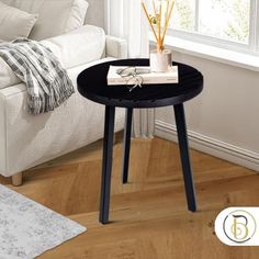 a small black table with a book and pencils on it next to a white couch