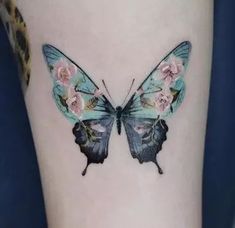 a blue butterfly with pink flowers on it's back side tattoo by the artist