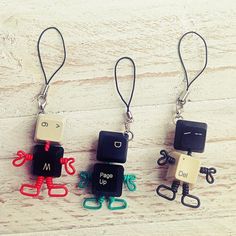 three different keychains with some type of characters attached to them on a wooden surface