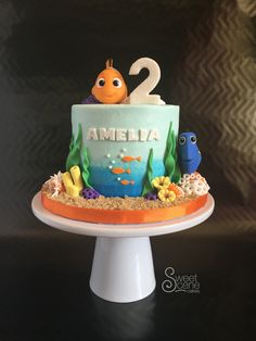 a two tiered birthday cake with an ocean theme and fish on the bottom layer