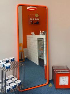 an orange mirror sitting in the middle of a room next to some boxes and baskets