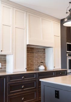 a kitchen with white and brown cabinets and an island in front of the stove top