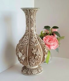 an ornate vase with flowers in the background