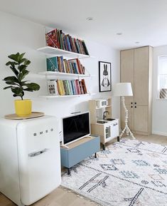 a living room filled with furniture and a book shelf next to a refrigerator freezer