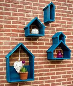 three blue birdhouses are hanging on a brick wall