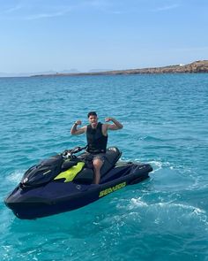 a man riding on the back of a jet ski in clear blue water with an island in the background