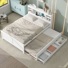 a white bed with drawers underneath it in a room next to a dresser and table